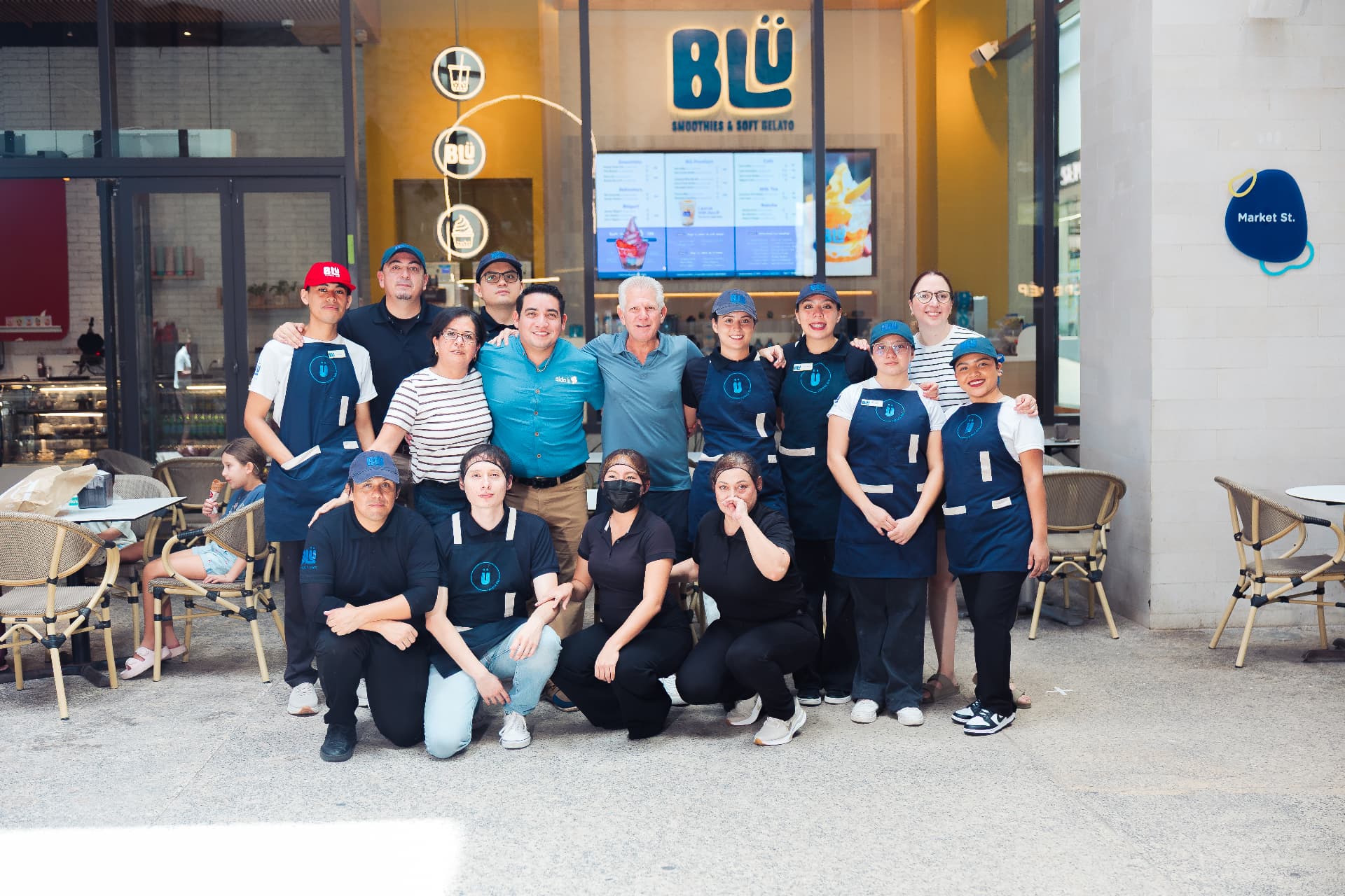 Equipo de BLÜ frente al local con letrero luminoso