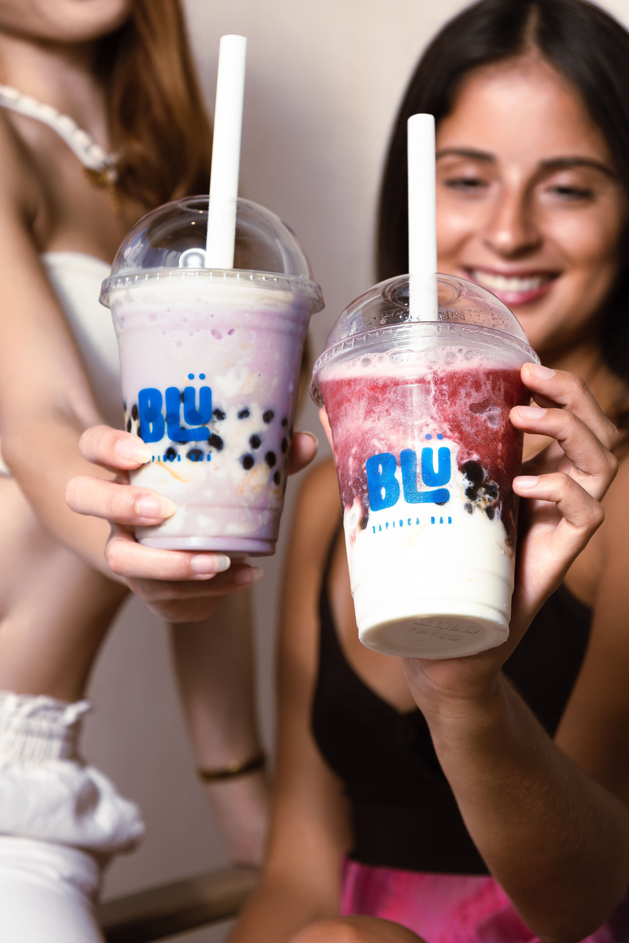 Dos personas brindando con bebidas de tapioca de BLÜ