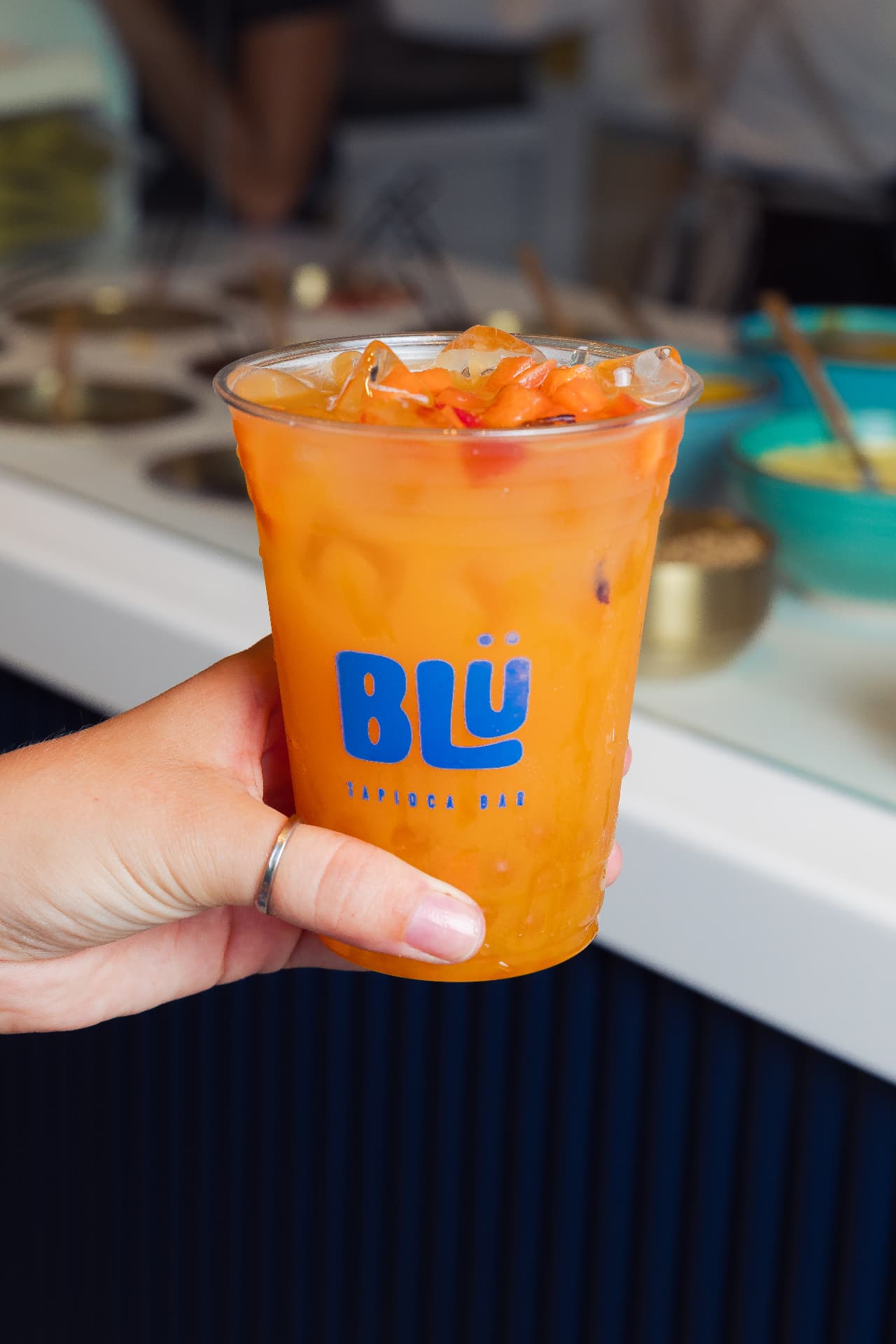 Mano sosteniendo bebida naranja con perlas de BLÜ