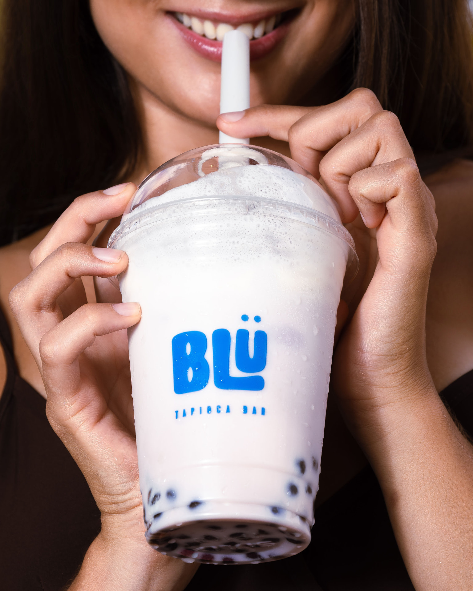 Sonrisa detrás de bebida rosada con tapioca de BLÜ